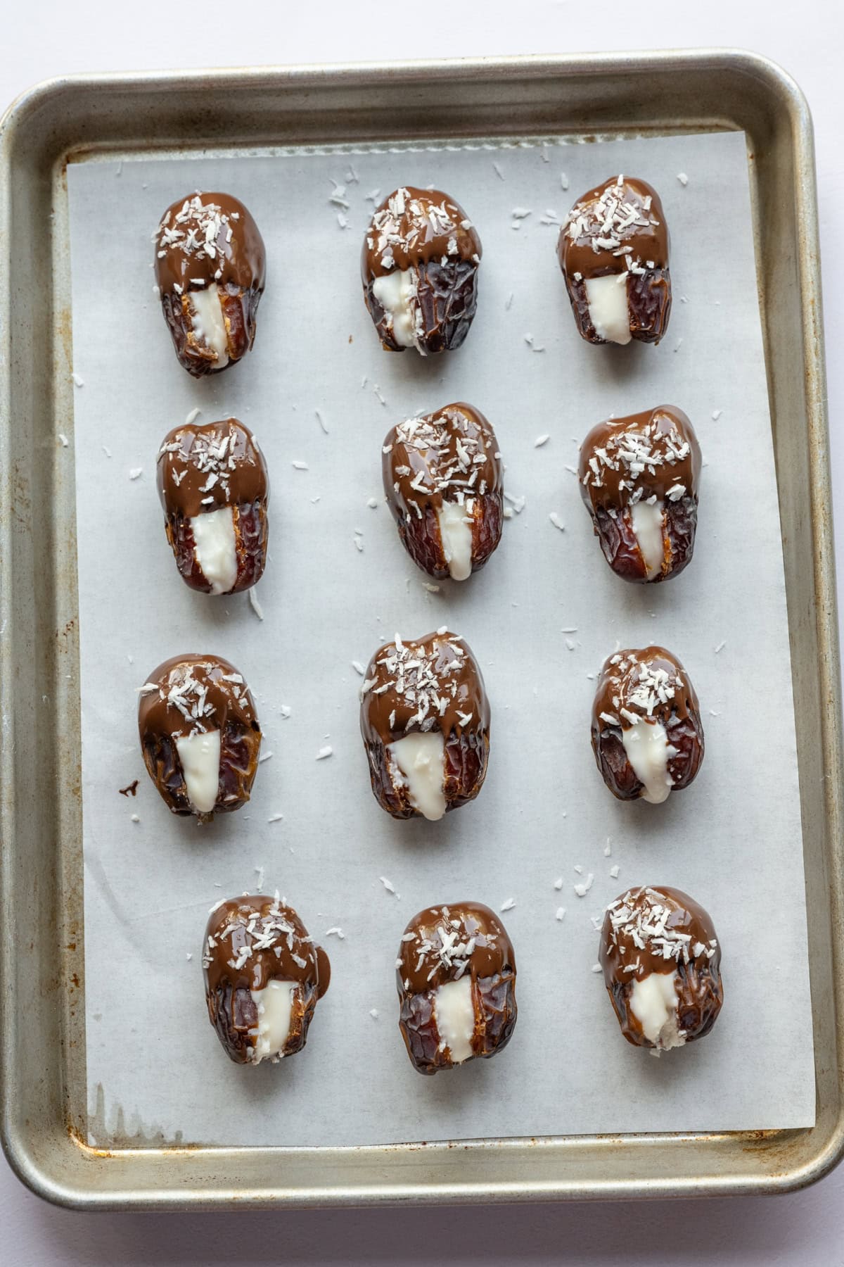 Dates farcies au beurre de noix de coco trempées dans du chocolat noir et saupoudrées de noix de coco plus râpée. 