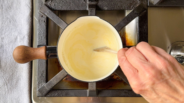 Inclination du beurre chaud et de la crème dans une casserole avec cuillère en bois