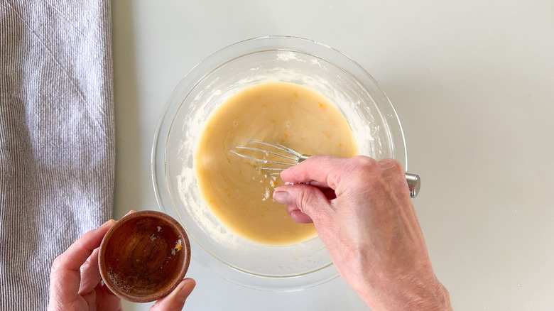 Ajout de zeste de citron et de sel à la ganache au chocolat blanc dans un bol en verre