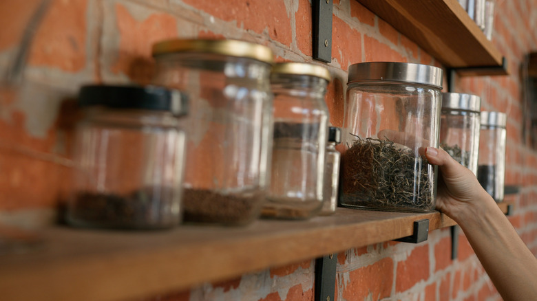 Une main qui cueille un pot d'épices dans l'étagère