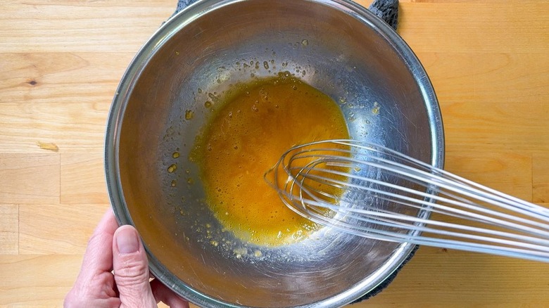 Fouetter les jaunes d'oeufs, l'ail et le vinaigre dans un bol en acier inoxydable