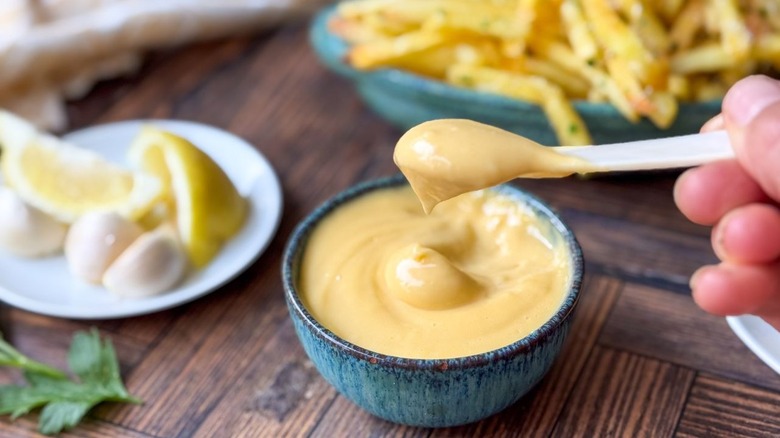 Aïoli à double truffe maison dans un bol et à la cuillère avec des frites et des citrons