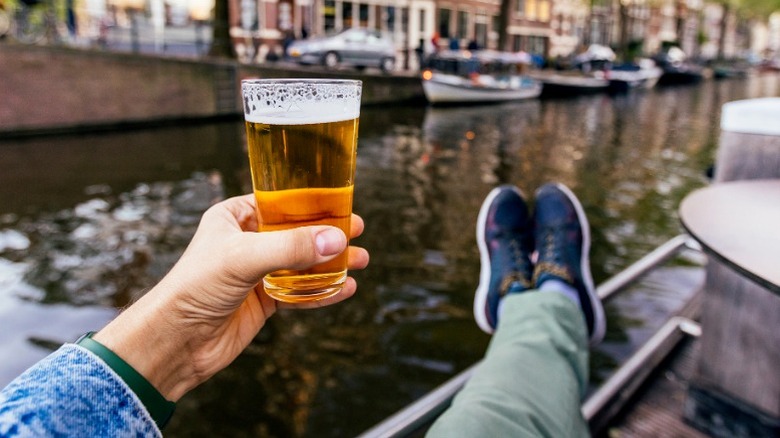 Personne tenant de la bière tout en se détendant par une rivière