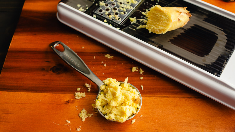 Une cuillère à soupe de gingembre frais râpé sur un comptoir en bois.