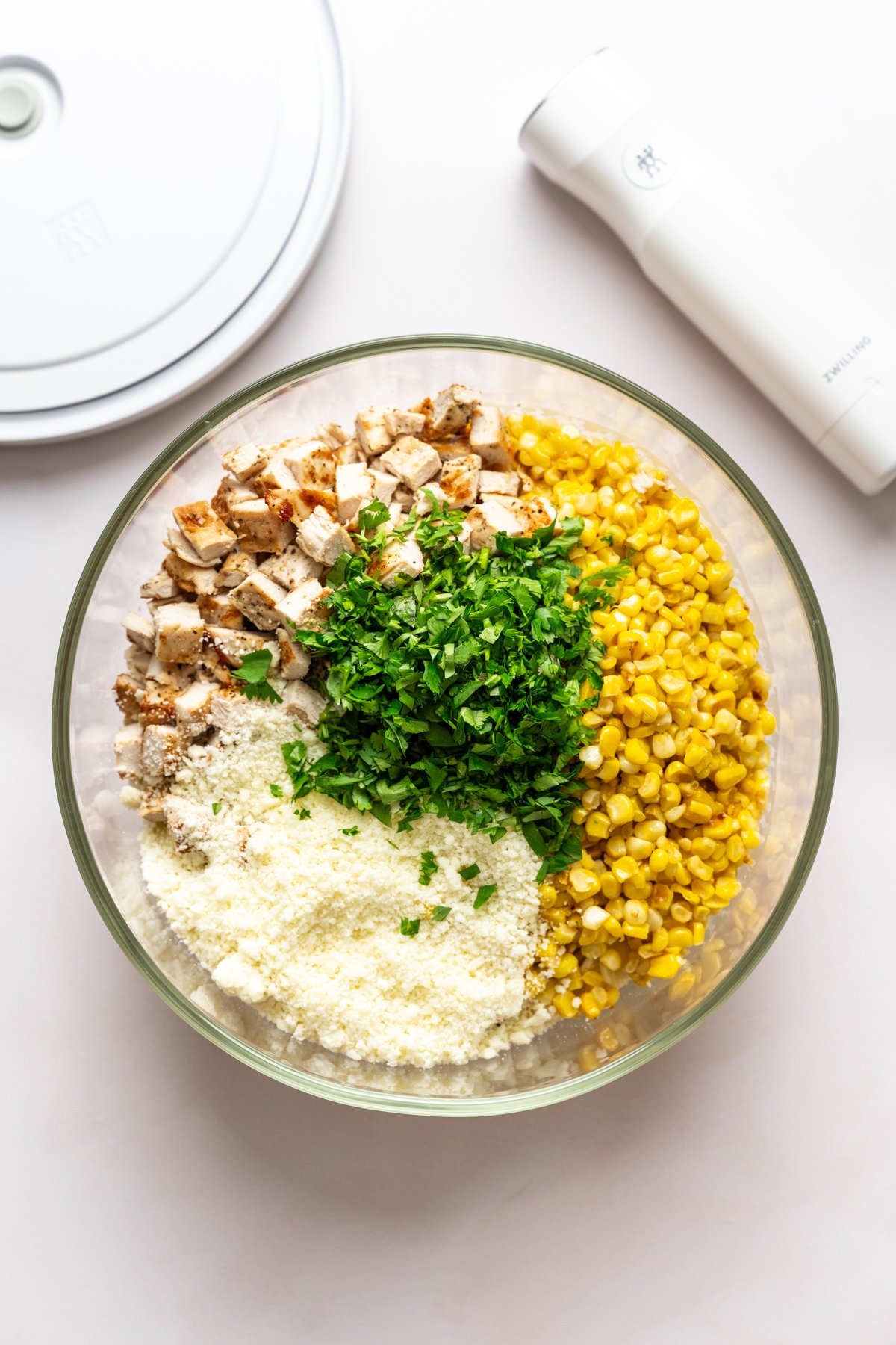 Ingrédients de salade de pâtes élote dans un grand bol en verre avant de mélanger.