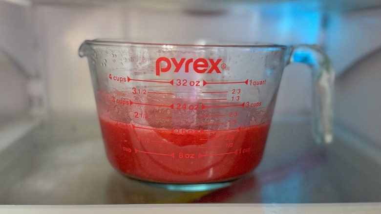 Purée de framboise dans un récipient à mesurer en verre au réfrigérateur