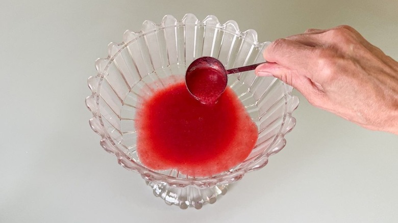 Utilisation d'une louche pour ajouter de la purée de framboise à un plat de bagatelle