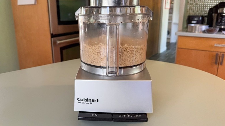 Noisettes finement hachées dans le bol du robot culinaire