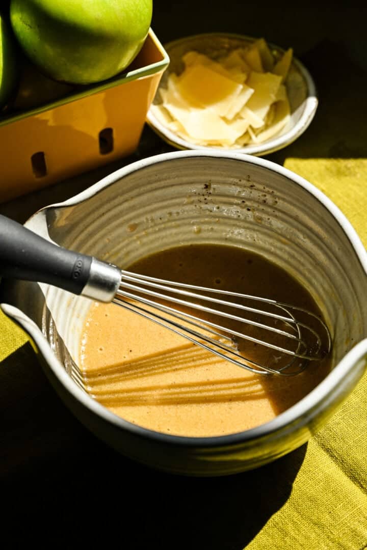 Vue rapprochée de la vinaigrette de cidre de pomme dans un bol avec fouet.