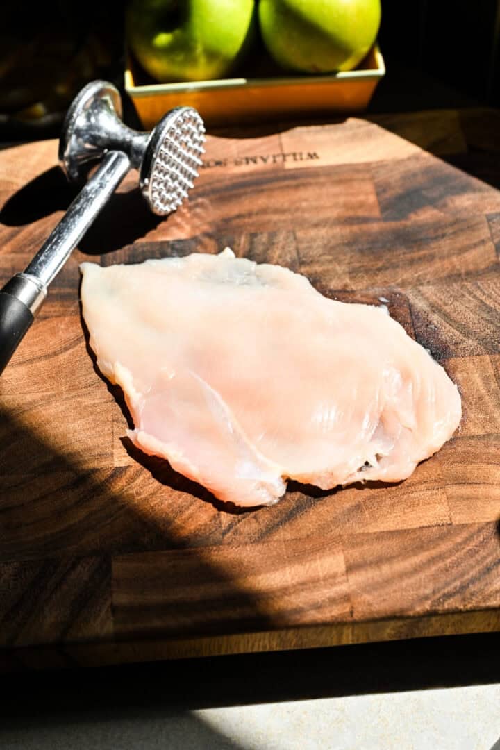 La poitrine de poulet a frappé finement sur une planche à découper en bois.