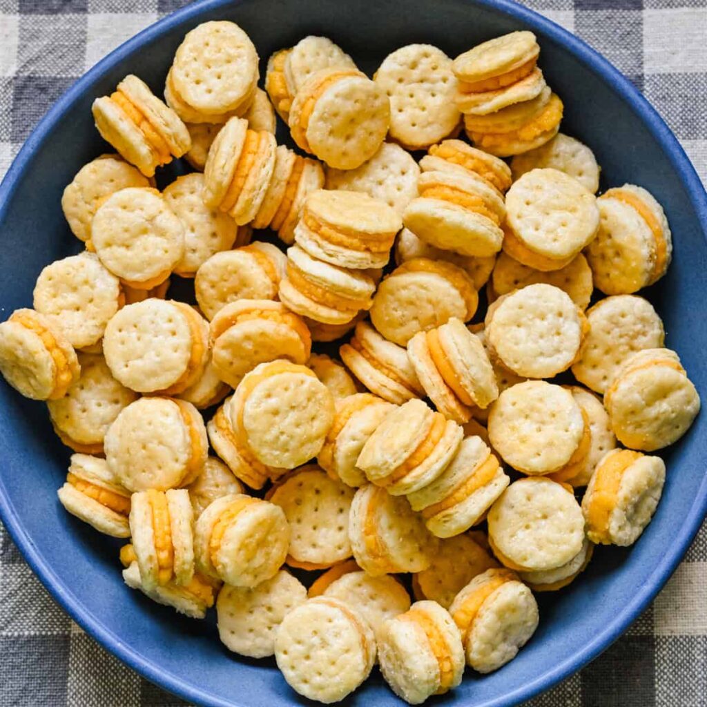 Overhead view of homemade ritz cheese cracker sandwiches in a blue bowl.