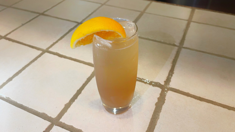 L'Amaretto Sour d'Olive Garden sur un dessus de bar blanc avec une garniture de quartiers d'orange