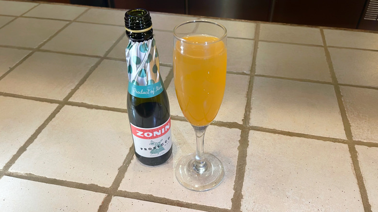 Le Peach Bellini d'Olive Garden sur un bar blanc à côté d'une mini bouteille de Prosecco