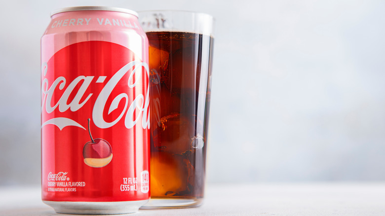 une canette de Cherry Vanilla Coke avec un verre rempli de soda derrière