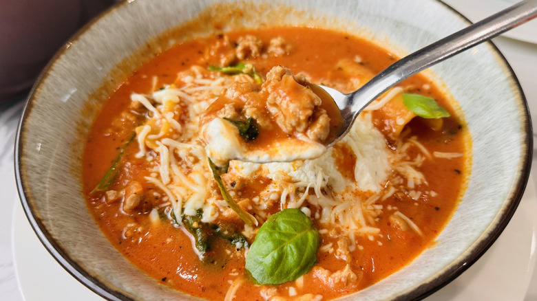 cuillère planant au-dessus d'un bol de soupe aux tomates et aux nouilles
