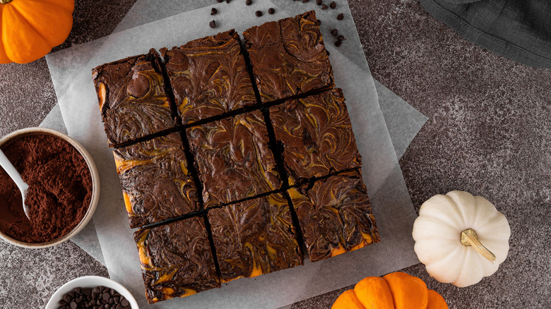 Brownies à la citrouille sur papier sulfurisé avec des citrouilles entières sur le côté