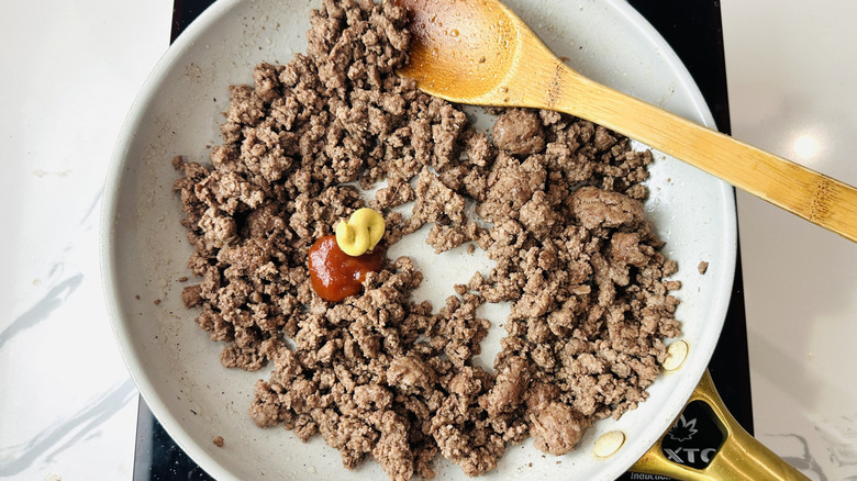 Bœuf cuit dans une poêle avec ketchup et moutarde