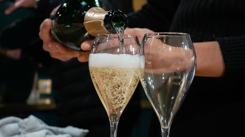Quelqu'un verse du vin mousseux dans un verre