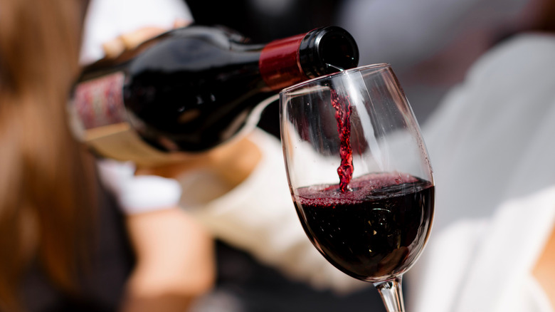 Une bouteille de vin rouge versée dans un verre.