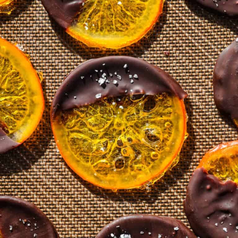 Tranches d'orange trempées dans du chocolat riche sur une surface texturée. Parfait pour un dessert décadent ou une gâterie festive.