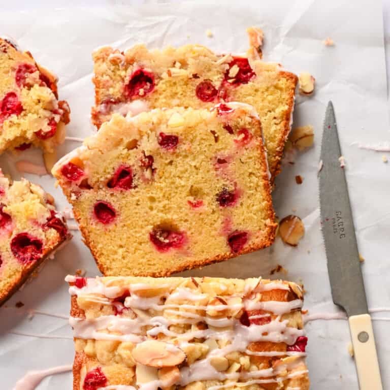 Vue aérienne du pain à l'orange et aux canneberges avec streusel aux amandes avec deux tranches coupées et posées à plat.