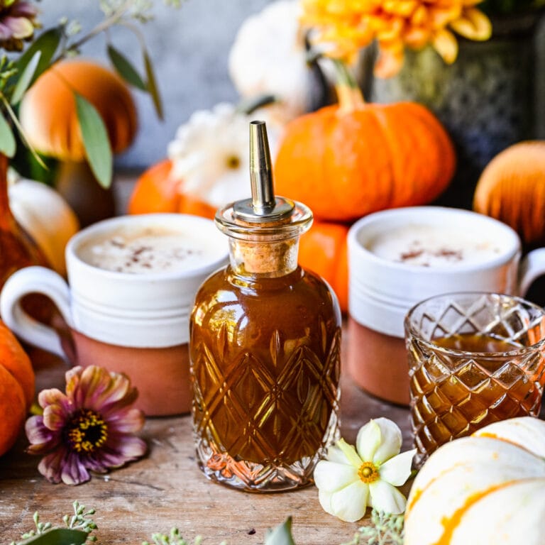 Sirop d'épices à la citrouille avec des décorations d'automne, des citrouilles, des fleurs et une ambiance automnale chaleureuse, parfait pour les recettes et les boissons d'automne saisonnières.