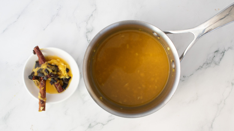 jus d'orange dans un pot en métal à côté d'une passoire pleine d'épices