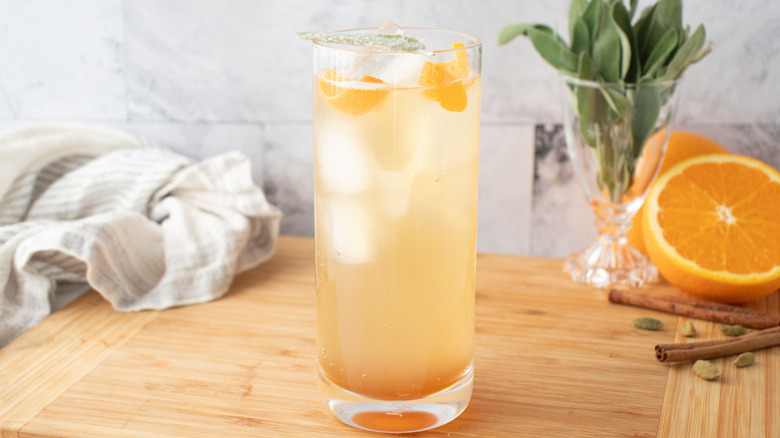 cocktail pâle de couleur orange dans un grand verre avec de la glace et des écorces d'orange