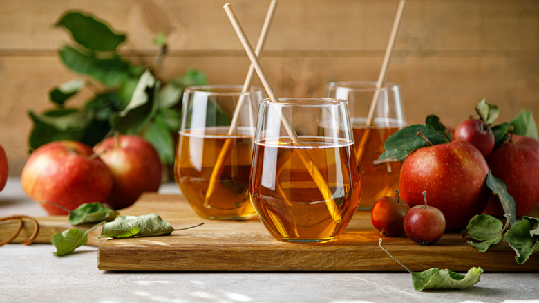 Deux verres de jus de pomme sur une surface en bois à côté de pommes entières
