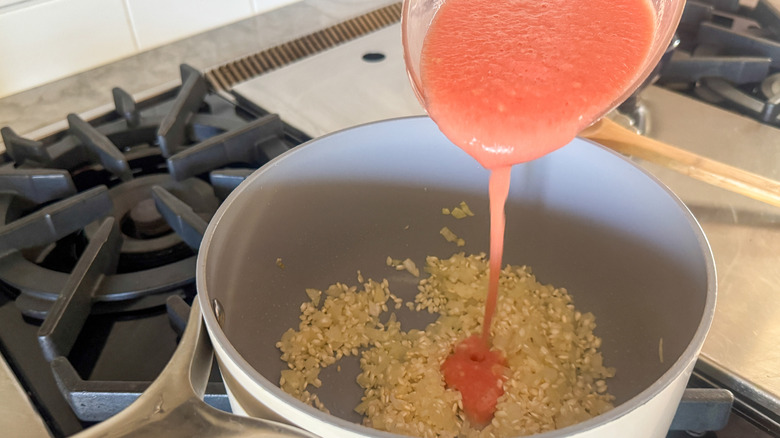 main versant la purée de tomates dans le pot