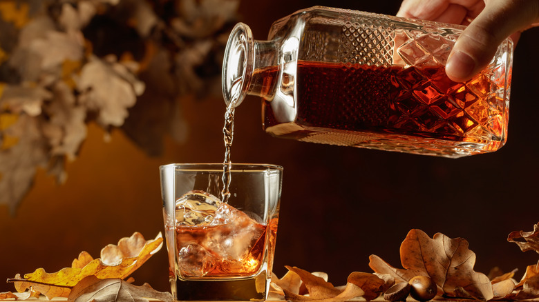 main versant du whisky dans un verre avec de la glace