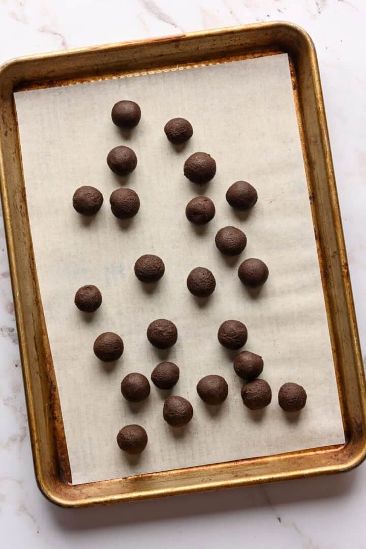 Ganache roulée en petites boules sur une plaque à pâtisserie.