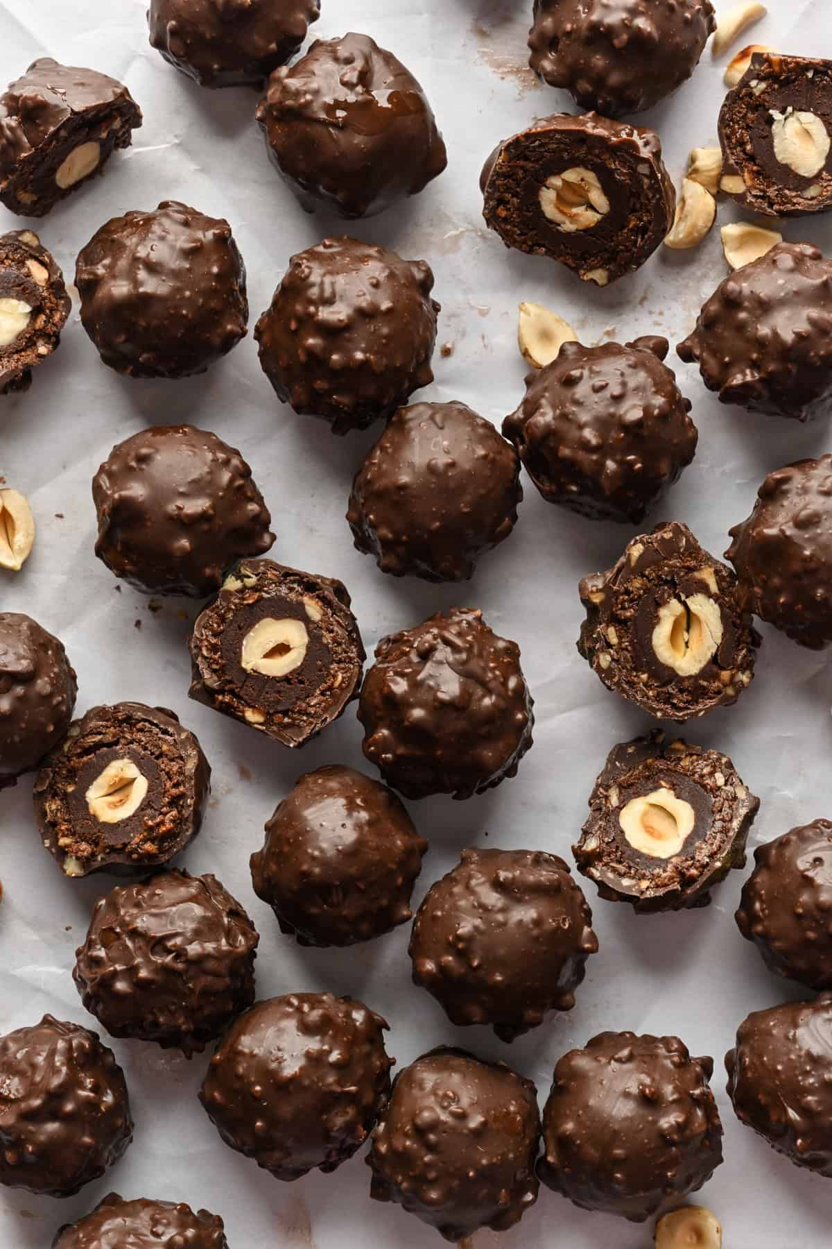 Vue aérienne des truffes ferrero rocher faites maison sur fond blanc avec quelques-unes coupées en deux.