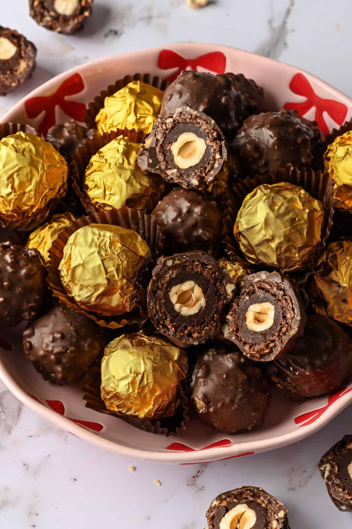 Vue rapprochée d'un bol rempli de truffes ferrero rocher maison, certaines enveloppées dans une feuille d'or et d'autres non emballées.
