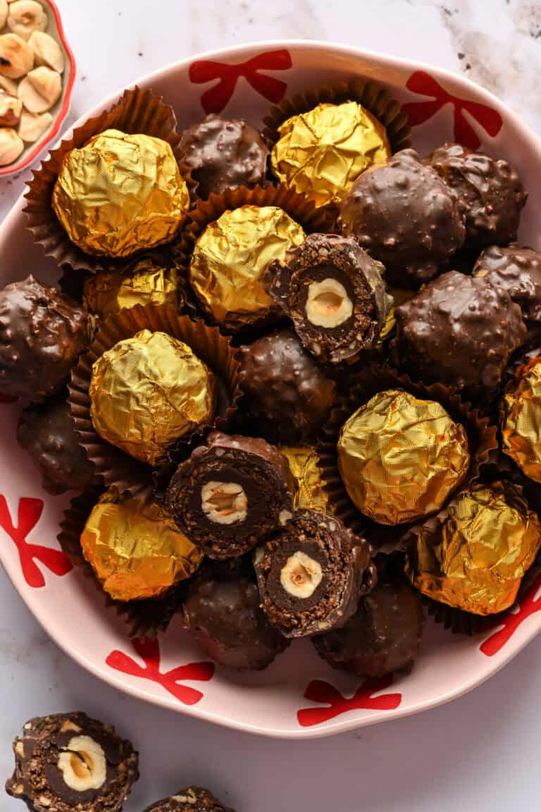 Vue aérienne d'un bol rempli de truffes ferrero rocher maison, certaines enveloppées dans une feuille d'or et d'autres non emballées.