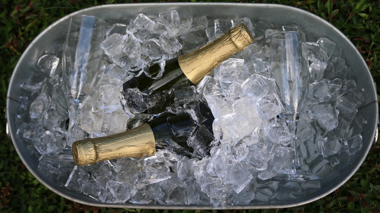 Deux bouteilles de Champagne sont situées dans un bac à glace en métal.