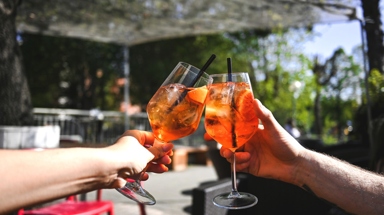 Des gens trinquant avec des cocktails Aperol Spritz