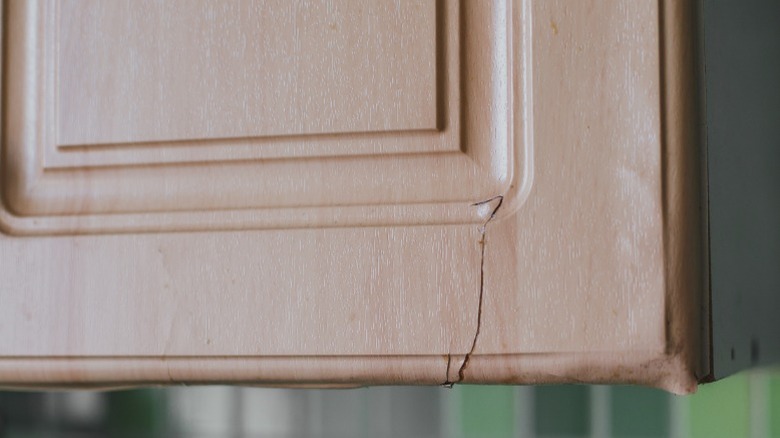 Une façade fissurée sur une armoire de cuisine en raison de dommages causés par la vapeur et la chaleur.