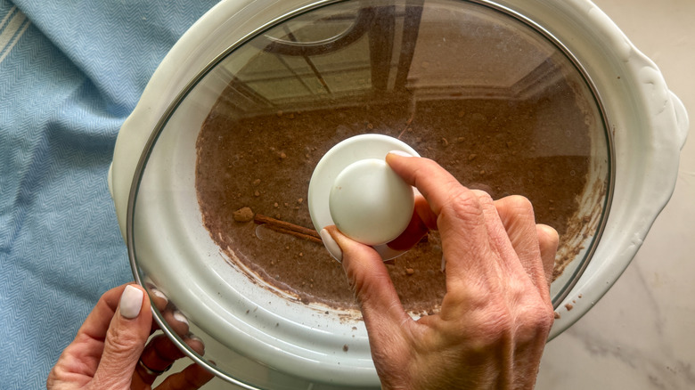 main ajoutant le couvercle à la mijoteuse