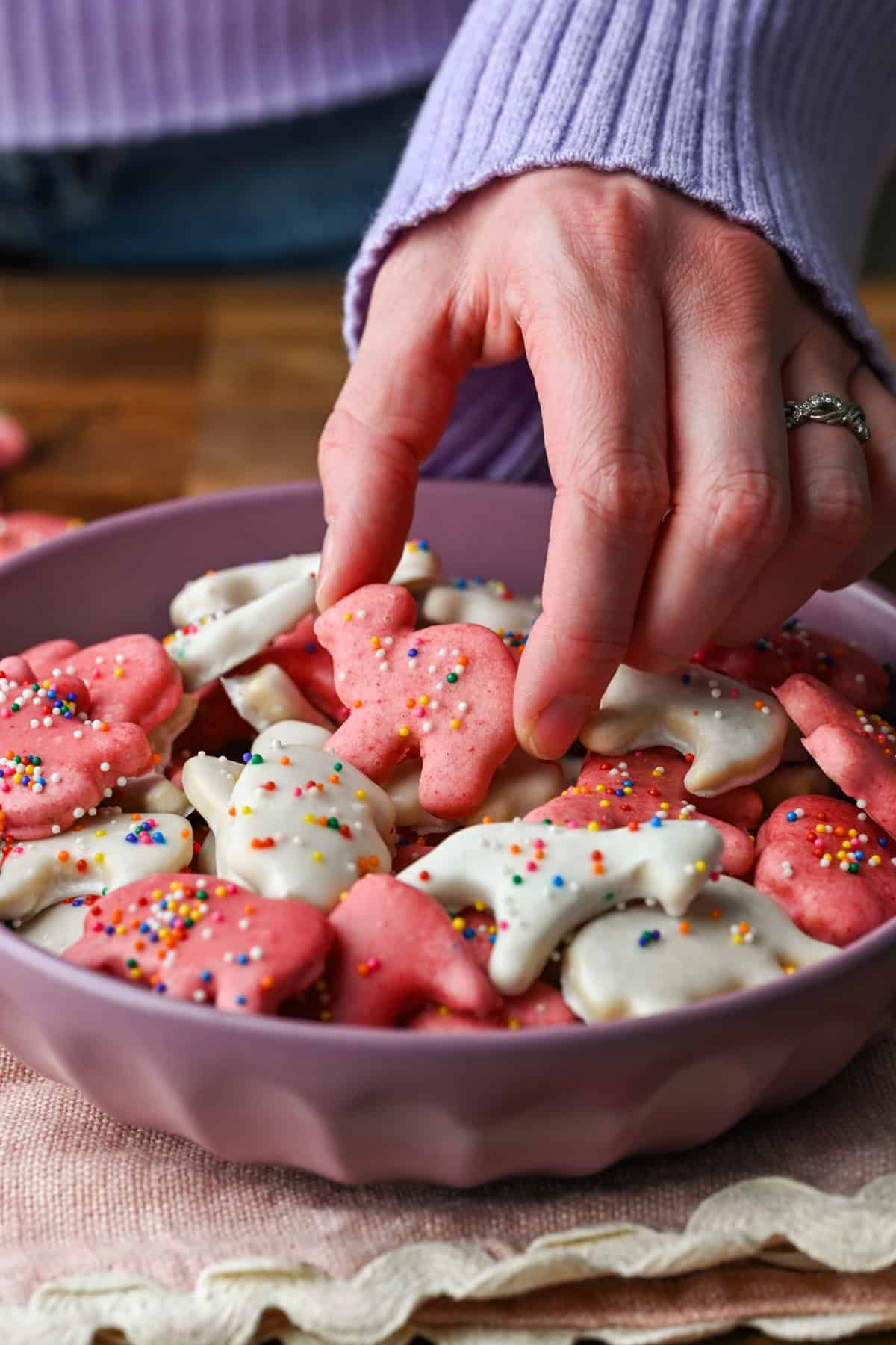 Vue de face d'un biscuit animal givré tenu par une main.