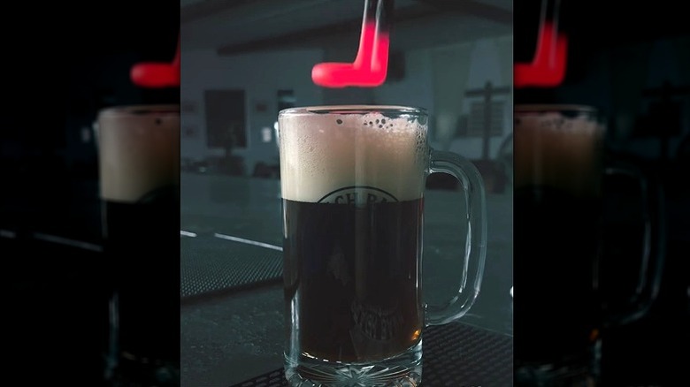 Poker chaud dans une chope de bière en verre avec tête mousseuse.