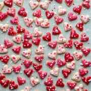 Vue aérienne de mini biscuits coeur avec glaçage rose et pépites de coeur sur papier parchemin.
