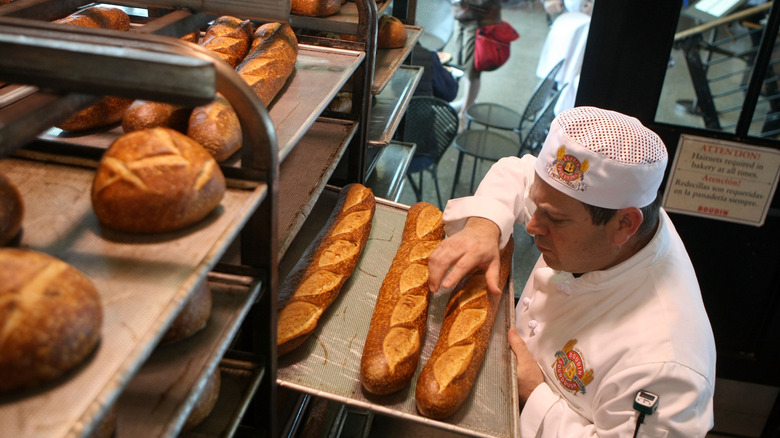 On voit un boulanger s’occuper des pains à la boulangerie Boudin à San Francisco.