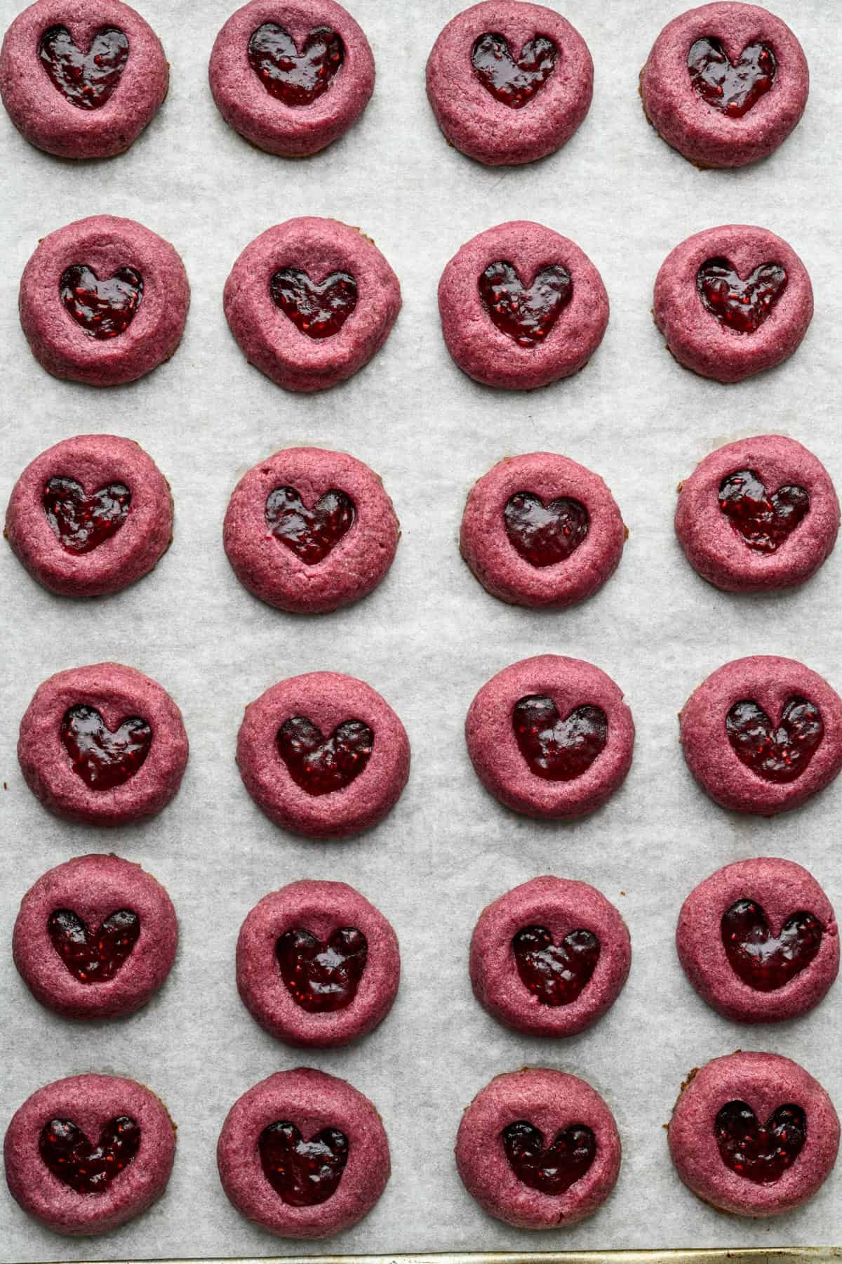 Biscuits à empreinte de cœur aux framboises sur une plaque après la cuisson.