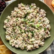 Salade de poulet aux canneberges et aux noix dans un bol à mélanger vert.