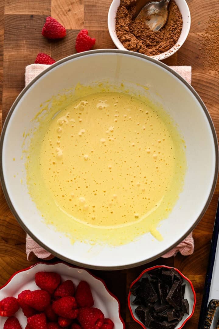 Oeufs et sucre fouettés ensemble dans un bol blanc.