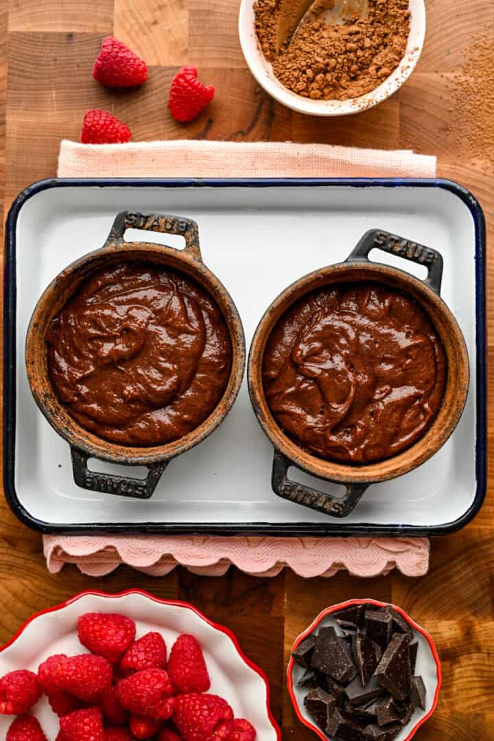 2 ramequins en fonte remplis de pâte à gâteau de lave au chocolat.