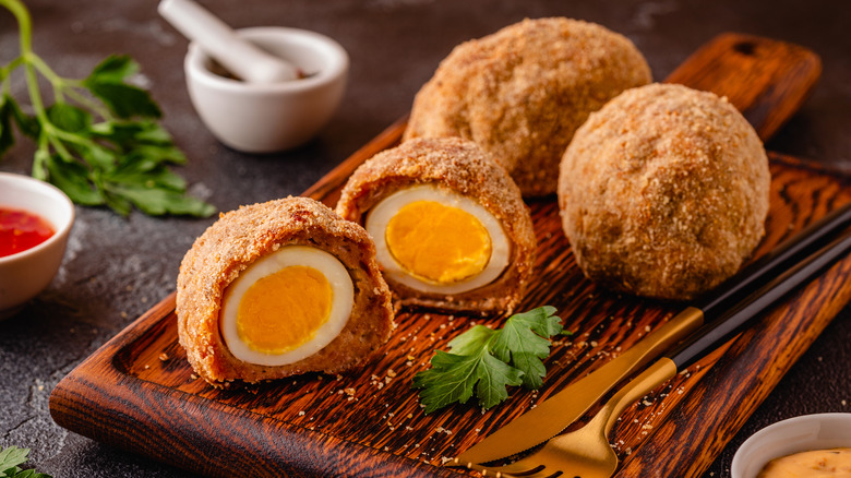 Les œufs écossais sont placés sur une planche à découper ; l’un est coupé au centre.