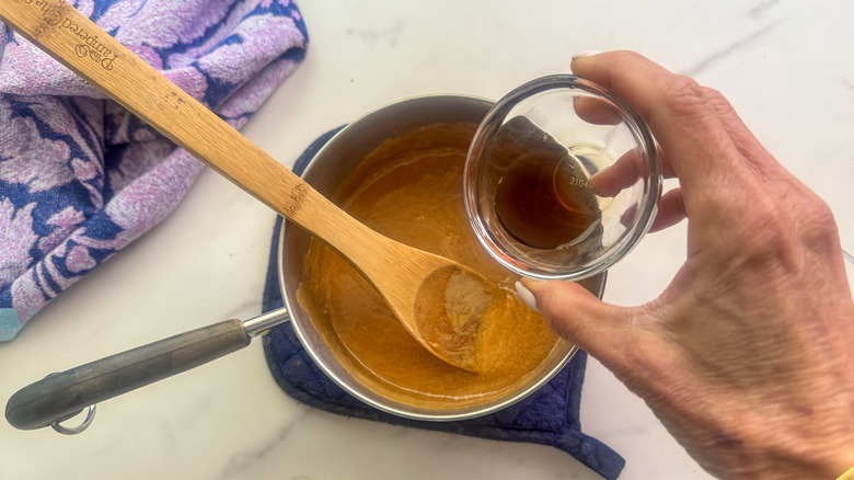 main ajoutant de la vanille au pot