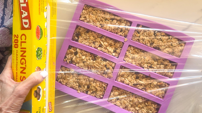 mains enveloppant le moule avec du film